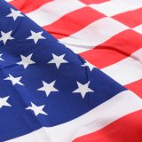Close-up of the United States flag: blue canton with white stars and red and white stripes on the fabric surface.